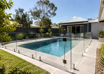 Frameless glass pool fencing around a backyard pool